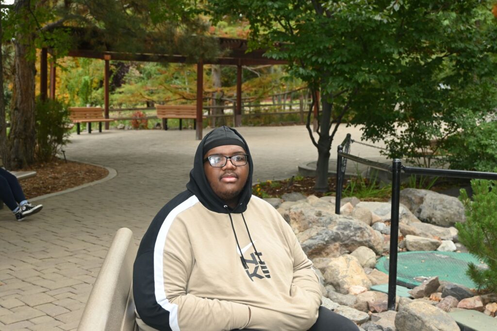 Portrait of a man on a park bench in carefully curated park setting.